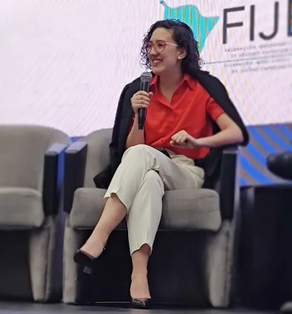 Lucía habla con micrófono sentada en un escenario de FIJE